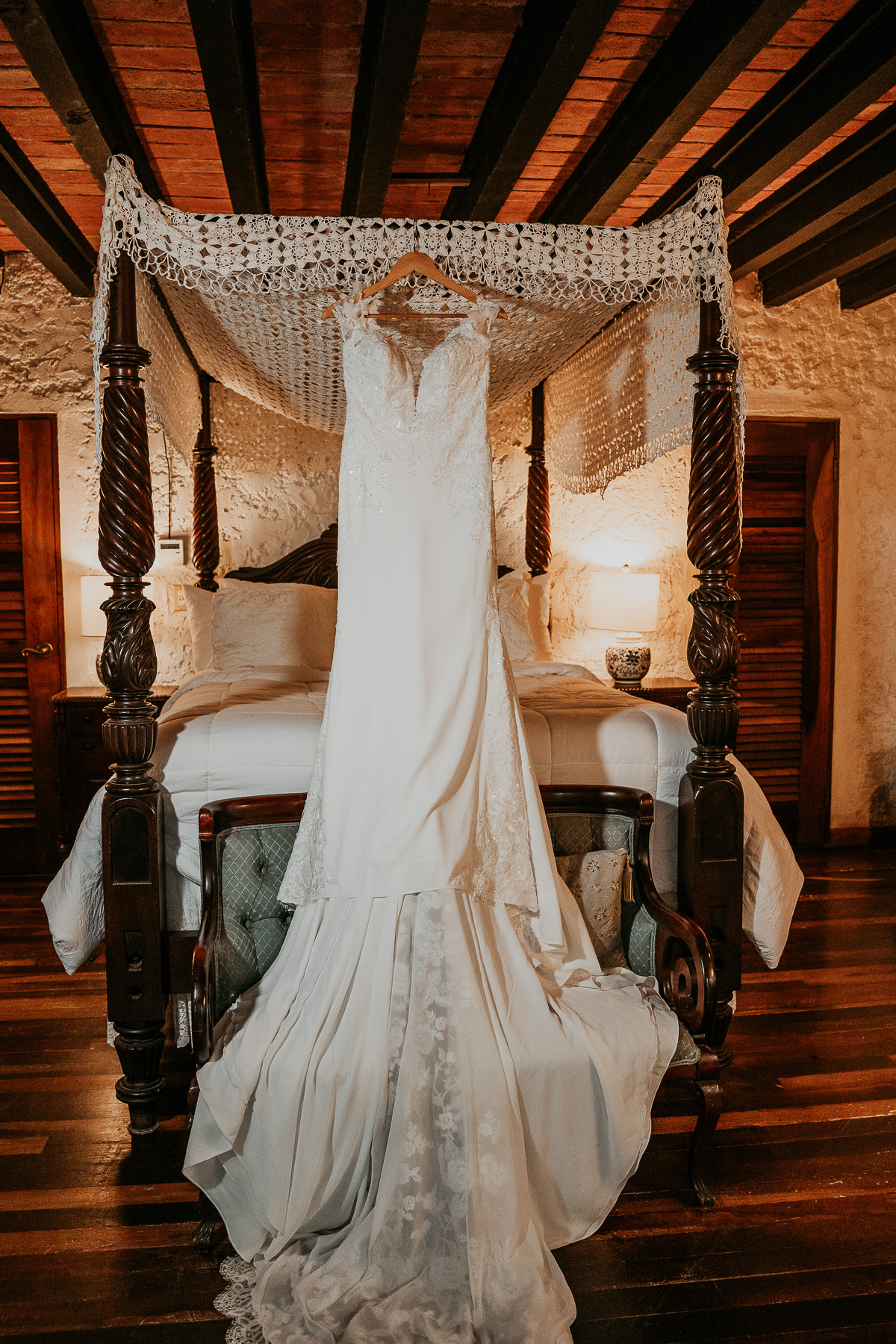 Stunning wedding dress with intricate lace detailing, hanging elegantly in a well-lit corner of Hacienda Siesta Alegre.