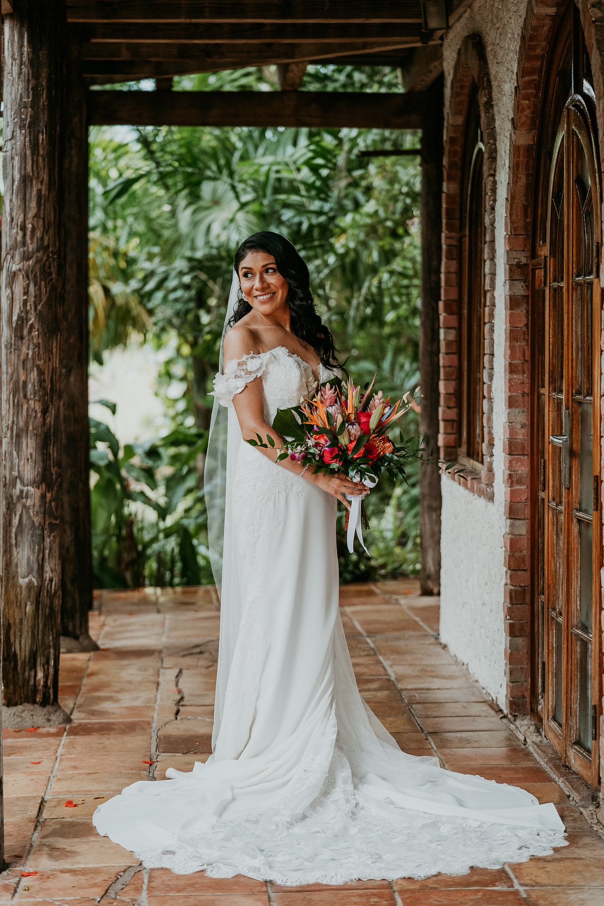 Bride preparing for her big day outside the Flamboyan room at Hacienda Siesta Alegre, with lush foliage and natural light surrounding her.