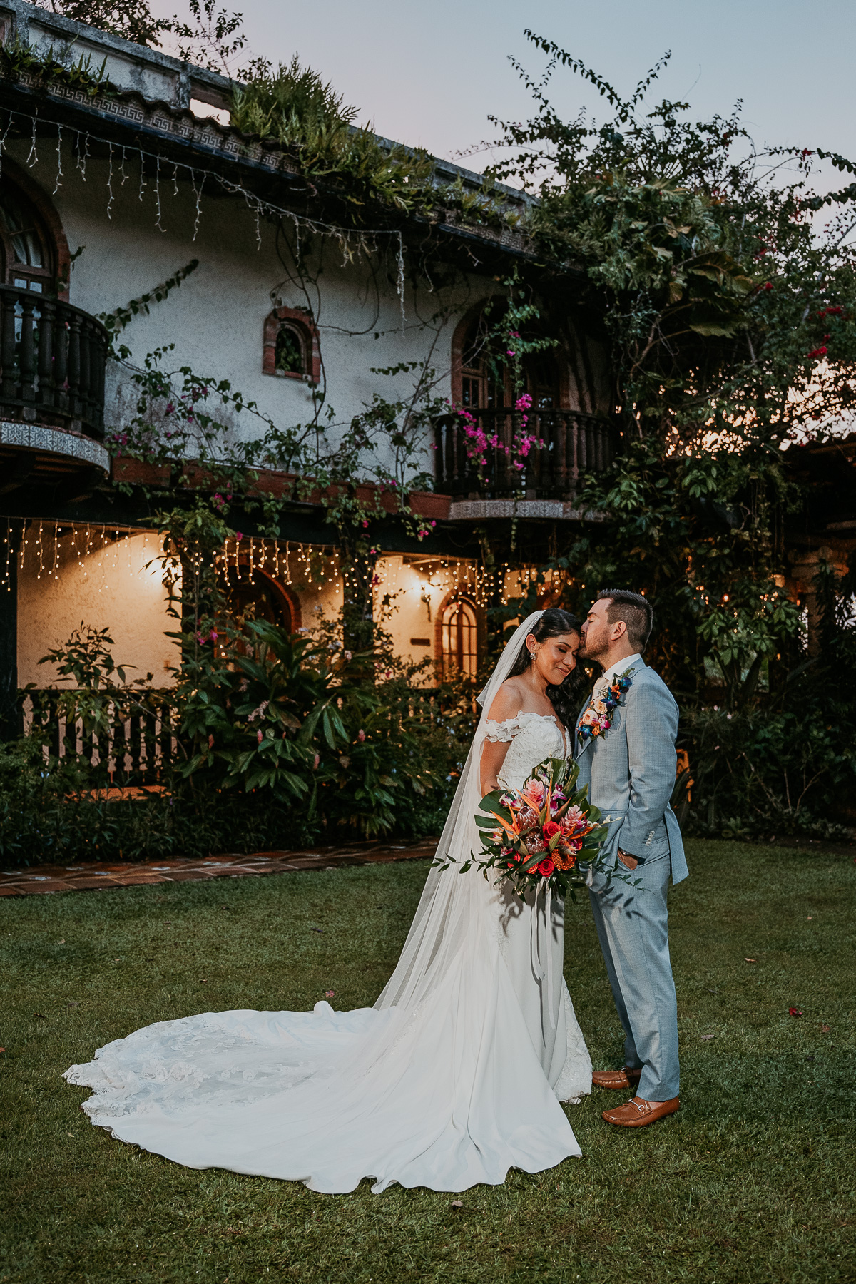 Bride and groom sharing a tender moment, framed by the natural beauty of Hacienda Siesta Alegre's lush greenery