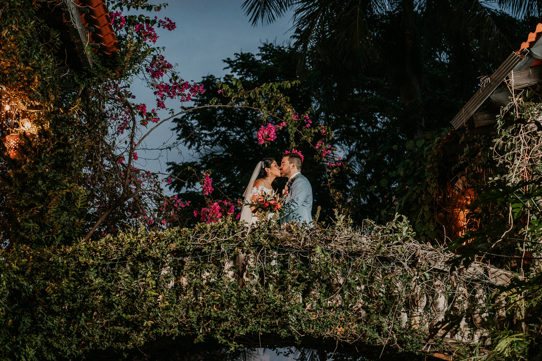 Bride and groom sharing a tender kiss on the bridge at night at Hacienda Siesta Alegre wedding celebration.