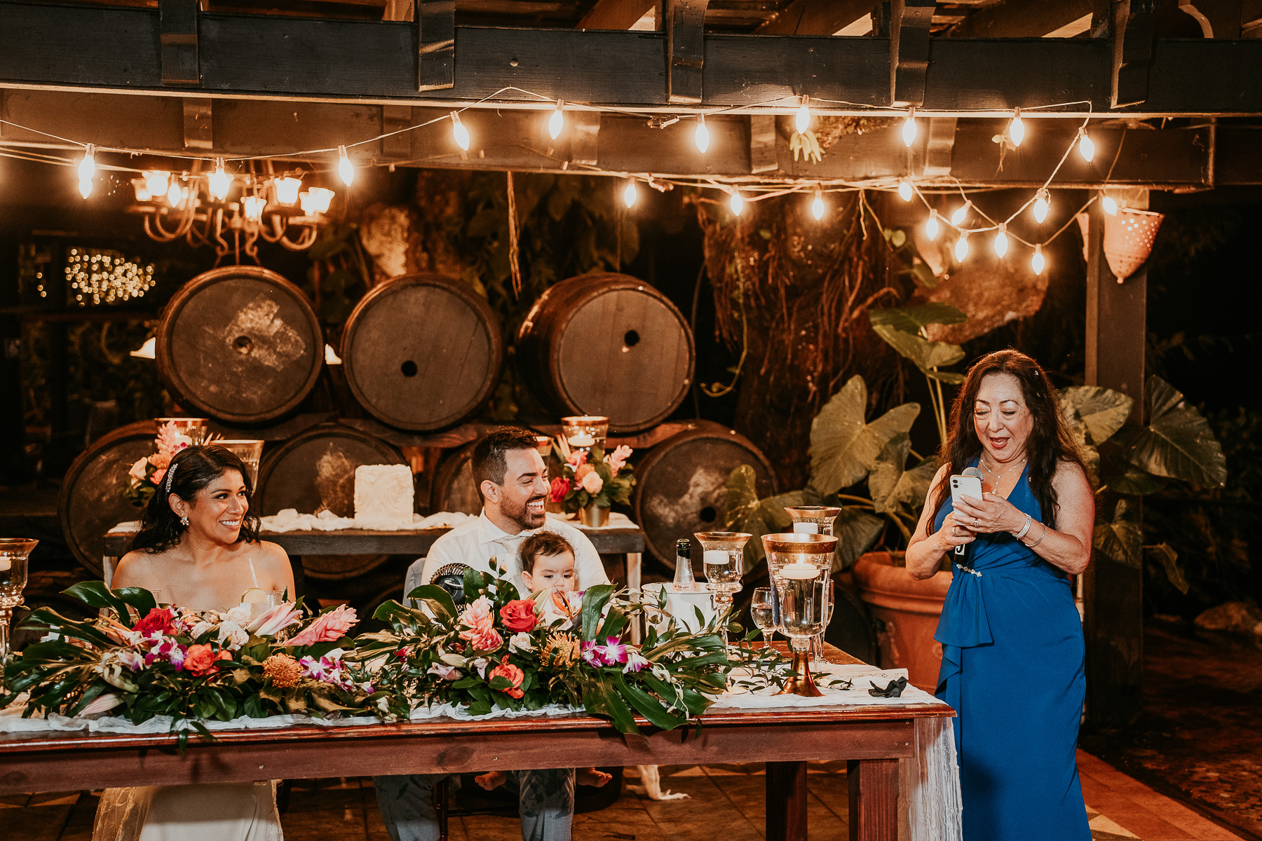 A touching speech being given during the wedding toast, with the bride and groom listening intently and smiling.