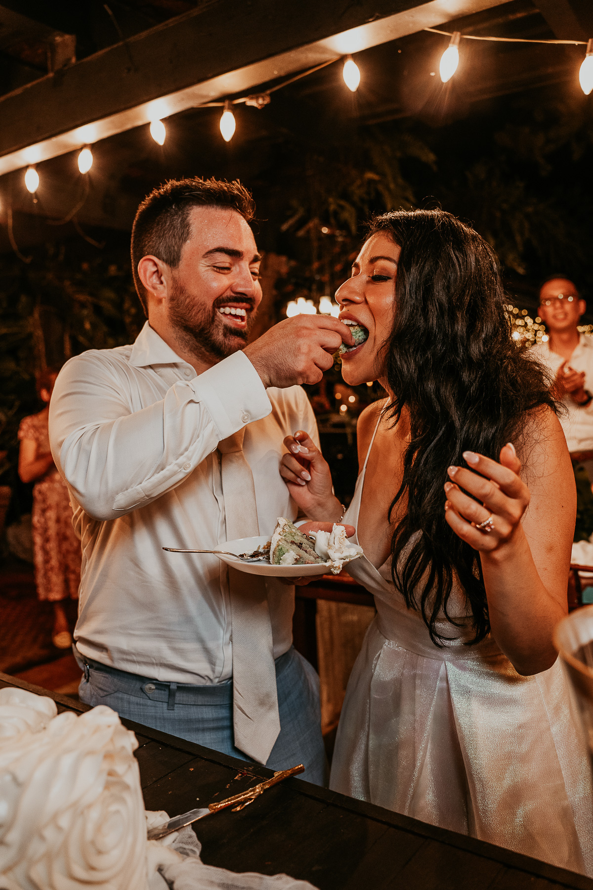 Couple sharing a joyful moment as they cut their elegant wedding cake surrounded by friends and family at Hacienda Siesta Alegre.