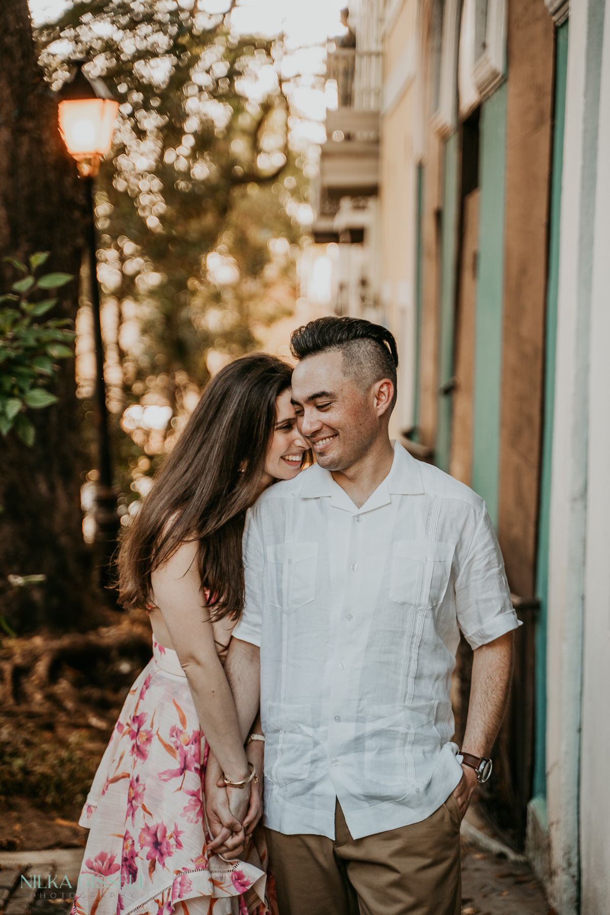 Romantic couple walking hand in hand along the historic Calle de las Monjas in Old San Juan, surrounded by colorful colonial buildings.