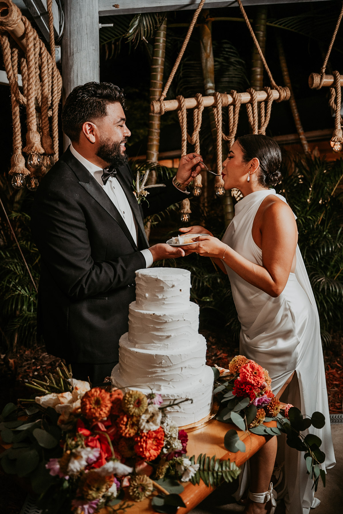 Candid photo of a newlywed couple laughing and feeding each other cake during their reception at Aldeana, one of the premier wedding venues in puerto rico.