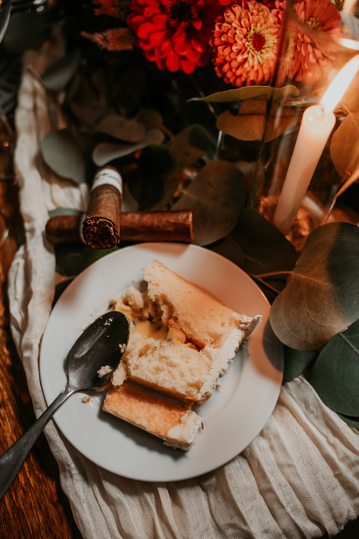 Half eaten wedding cake in plate with artisanal cigars on the side.