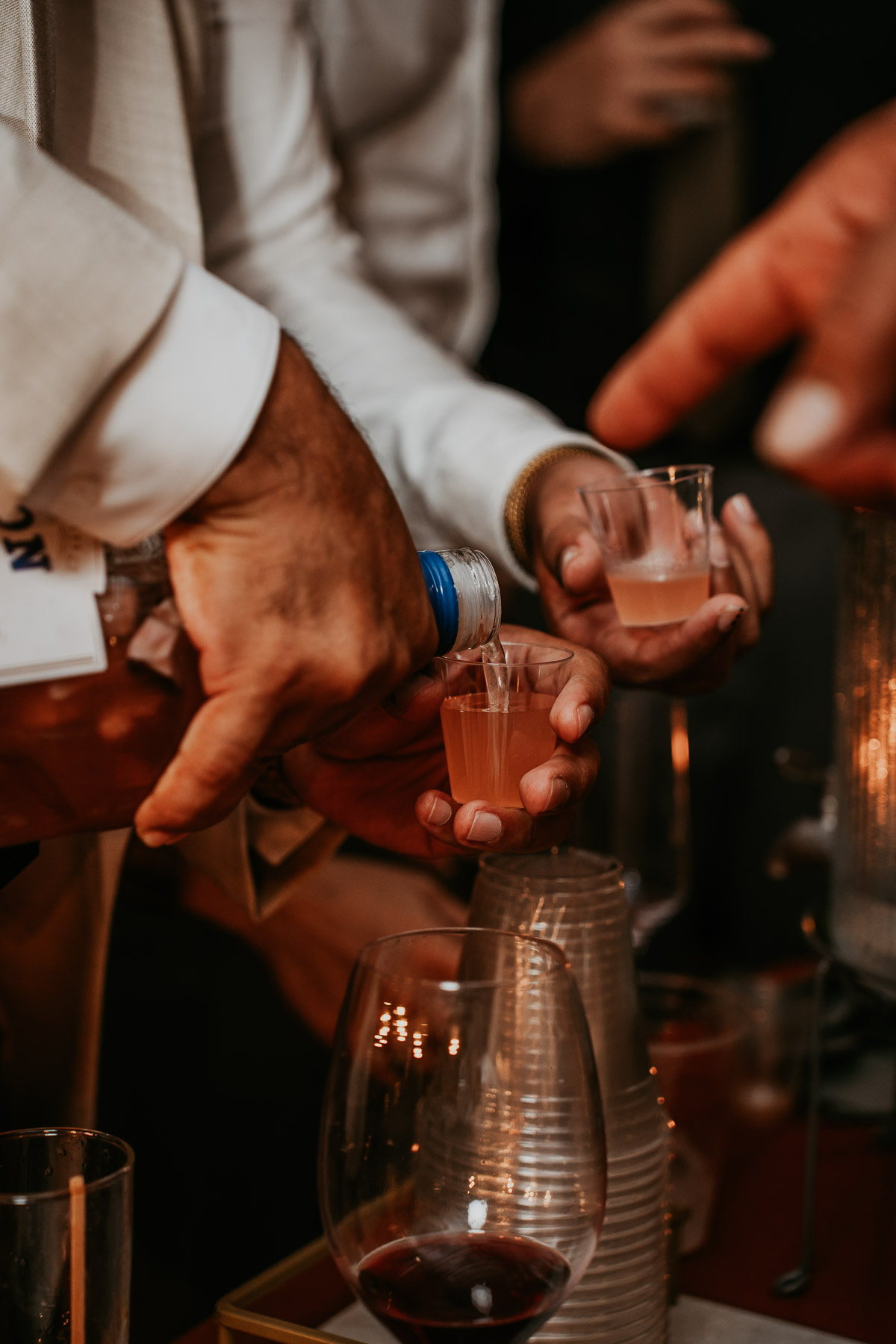 Boricua wedding guests pouring and drinking homemade local pitorro from the gancho bottle at a mountain reception.