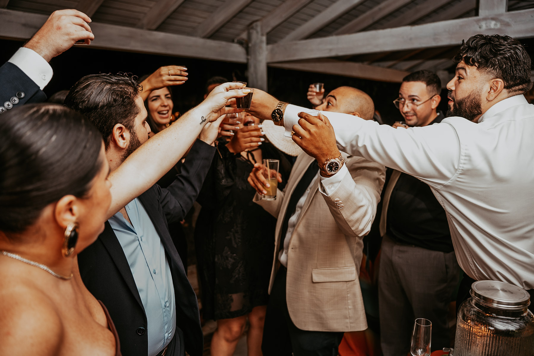 Boricua wedding guests pouring and drinking homemade local pitorro from the gancho bottle at a mountain reception.