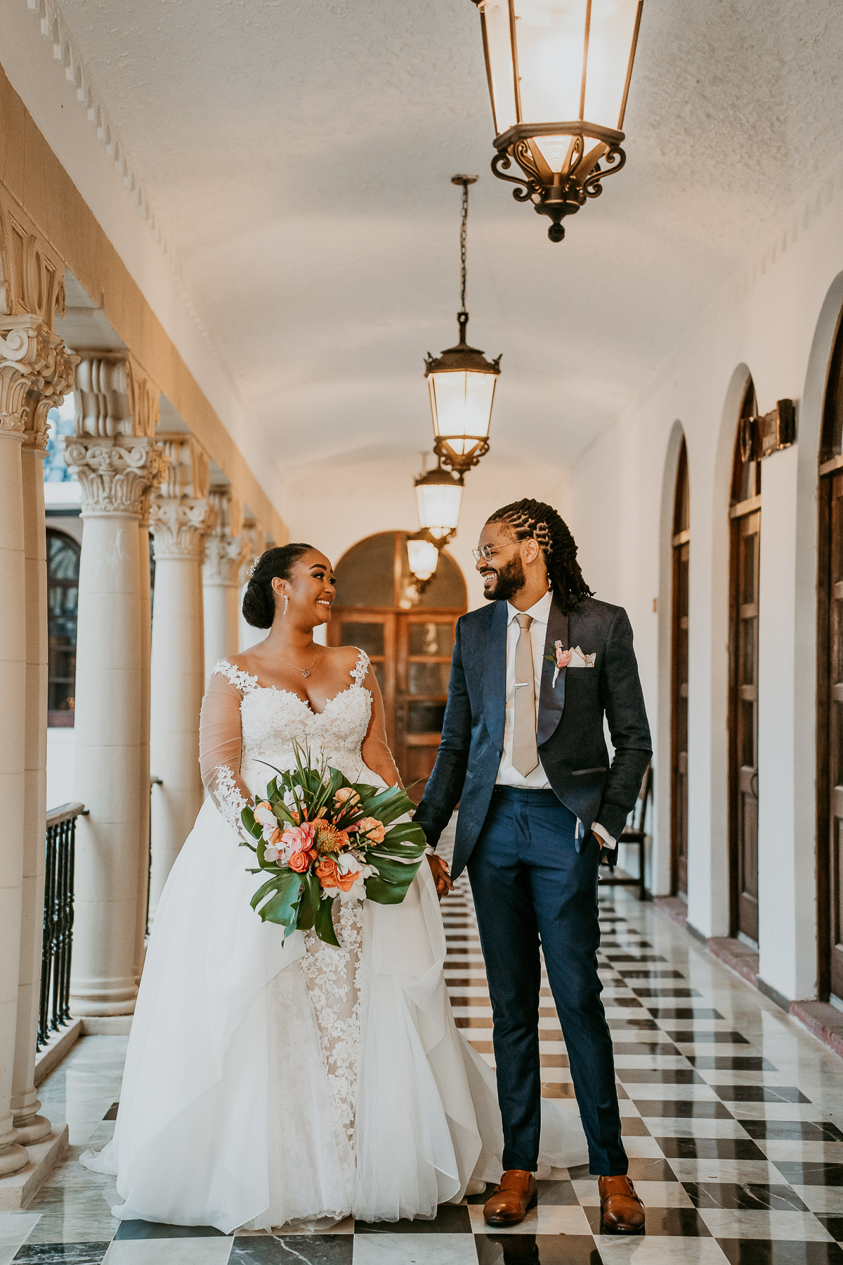 Bride and Groom Walking Hand in Hand Through Casa de España’s Historic Corridors