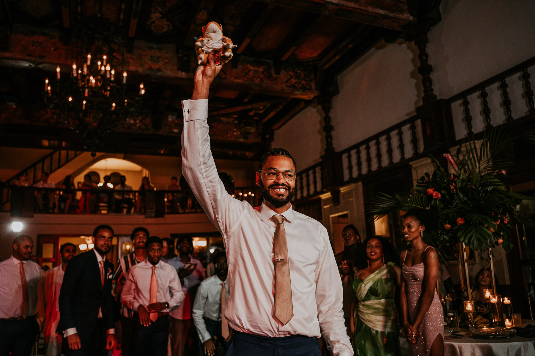 New wedding traditions for garter toss of a coqui frog at Casa de España wedding.