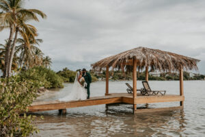 Newlywed couple posing next to the wedding gazebo with the beach and Caribbean horizon behind them at Copamarina Beach Resort.