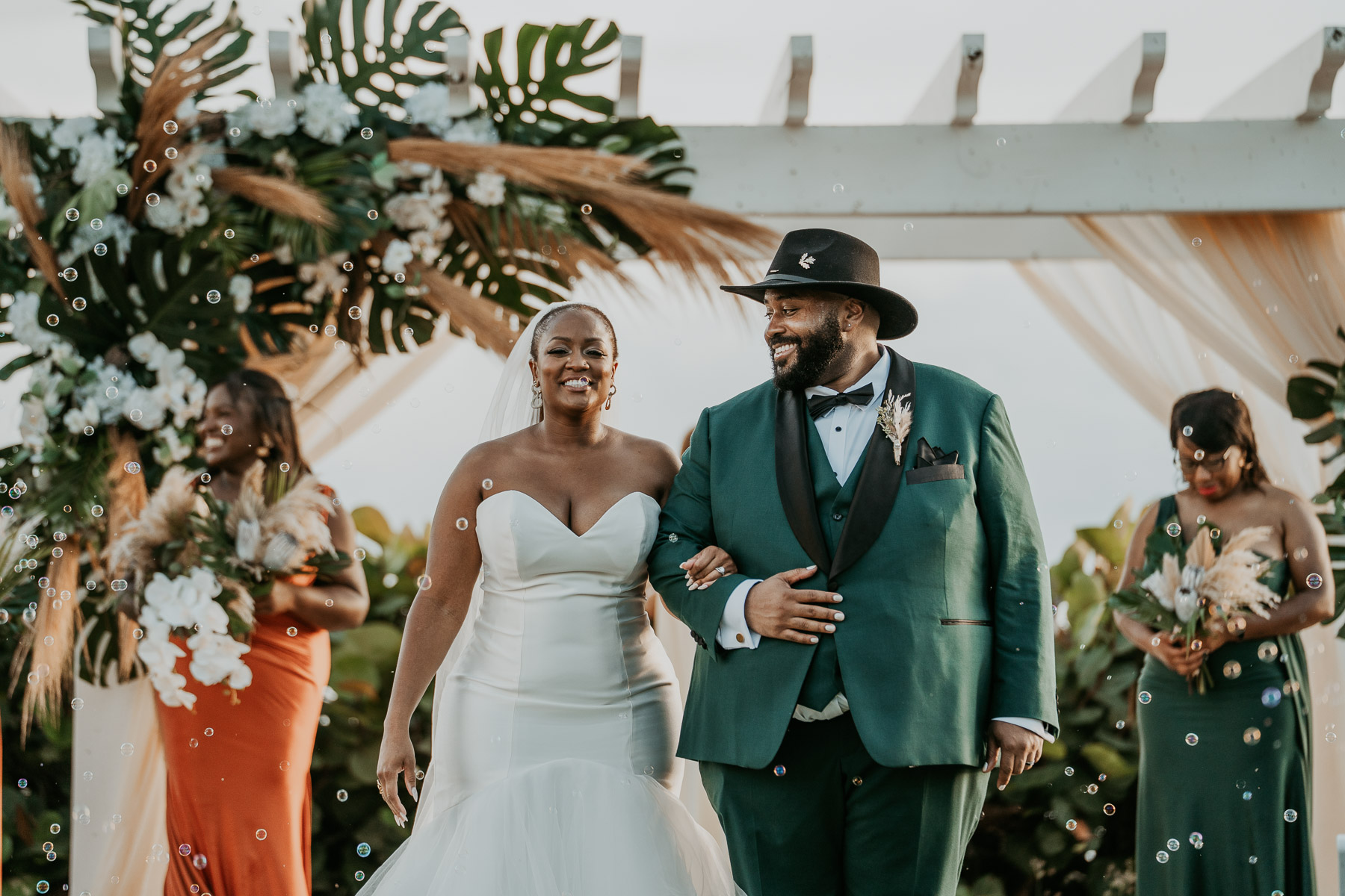Newlywed couple walking through a joyful bubble send-off surrounded by their wedding guests.