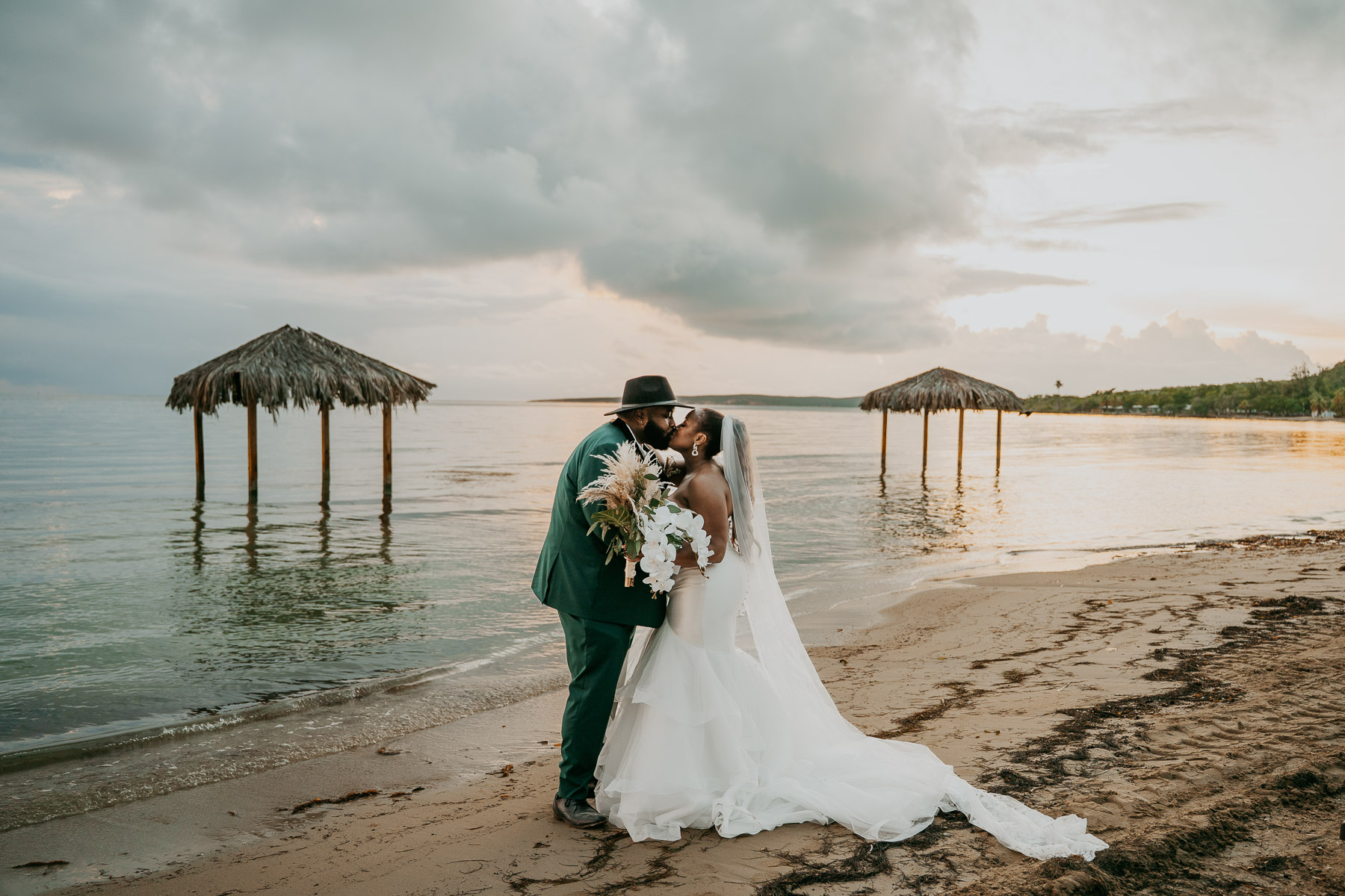 African American newlywed couple embracing during their Copamarina wedding portraits in Puerto Rico with the beach and sunset in the background.