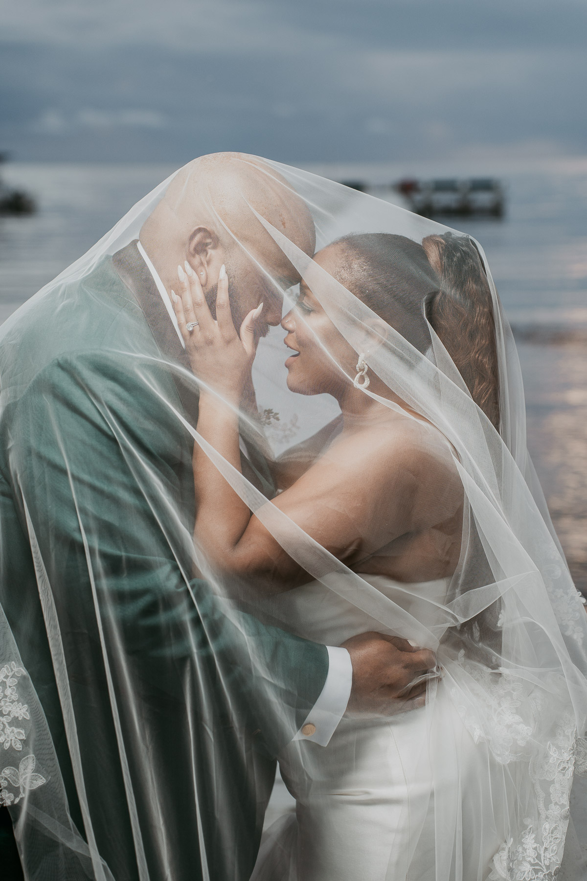 Newlywed couple embracing beneath the bride's veil during an intimate wedding portrait.