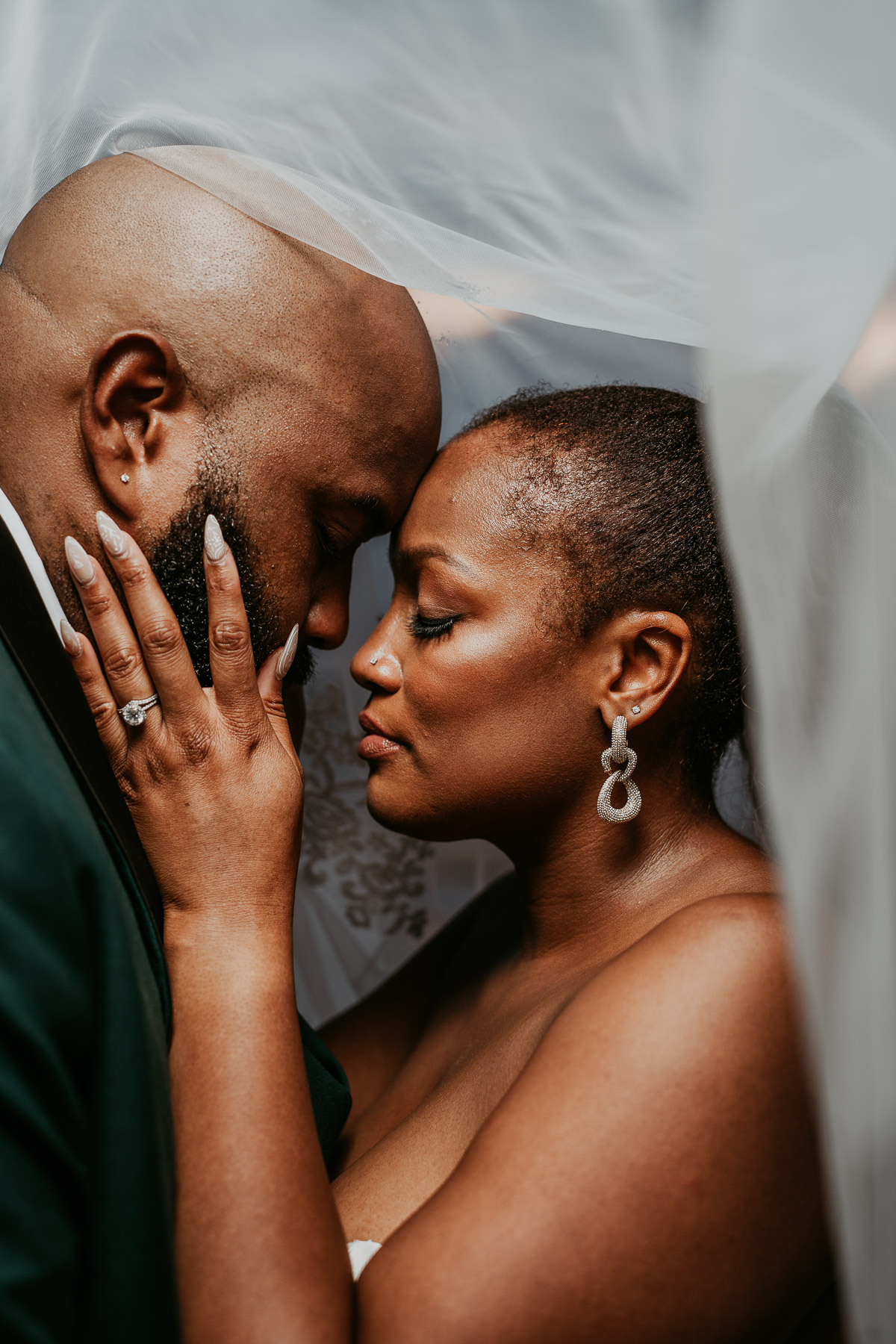 Newlywed couple embracing beneath the bride's veil during an intimate wedding portrait.
