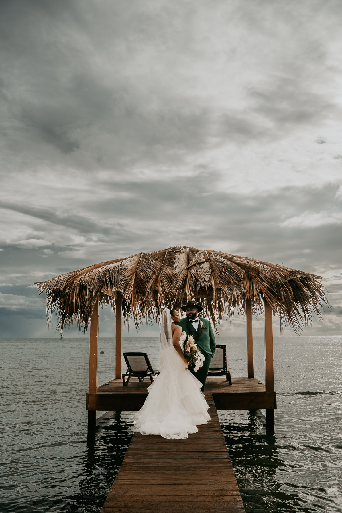 Newlywed couple posing next to the wedding gazebo with the beach and Caribbean horizon behind them at Copamarina Beach Resort.