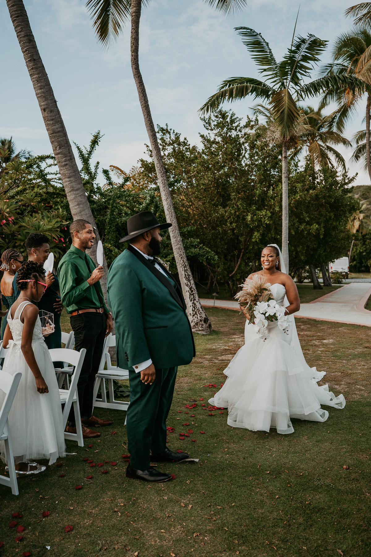 Bride and groom walking together toward their wedding ceremony surrounded by tropical greenery.