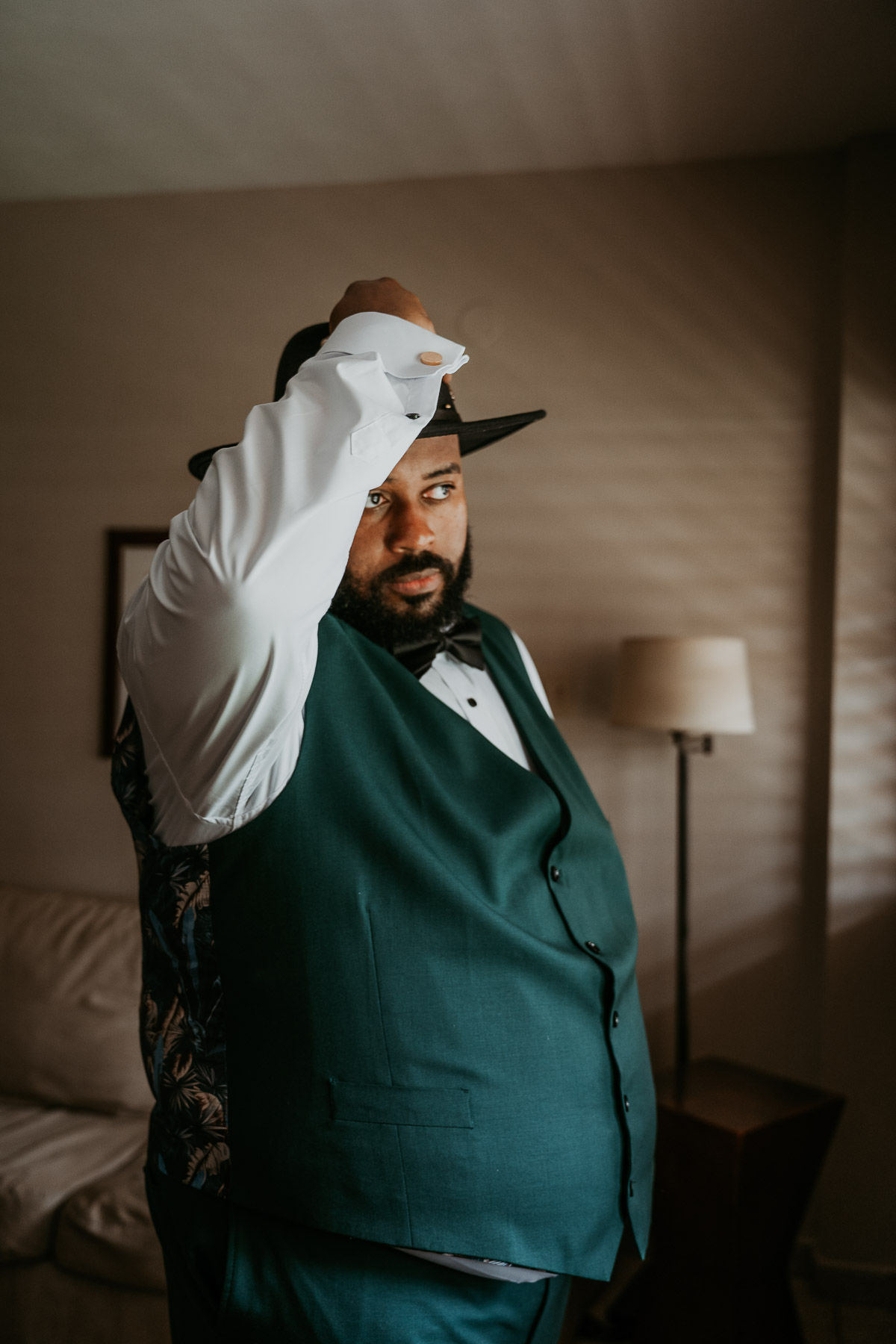 Groom putting on his hat while getting ready for his wedding at Copamarina Beach Resort.