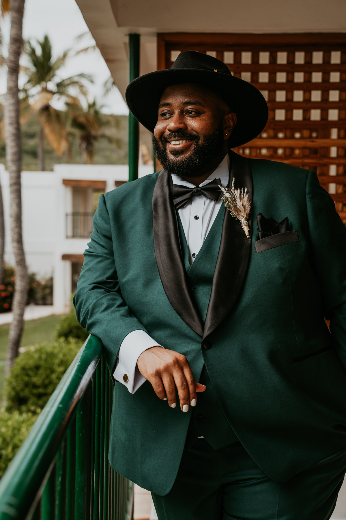 Groom posing for wedding portraits surrounded by the tropical landscape at Copamarina Beach Resort.
