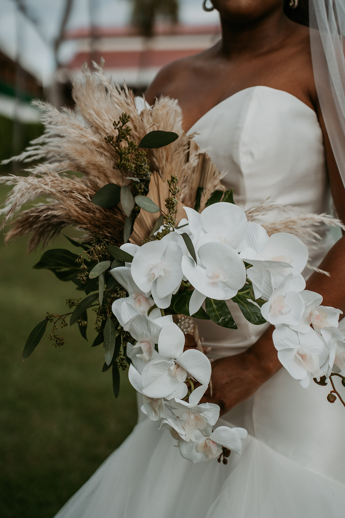 Close-up of the bride's wedding bouquet featuring fresh flowers and tropical greenery.