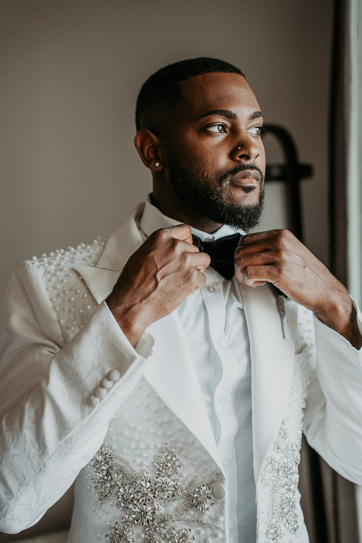 Groom preparing for wedding ceremony with natural light in resort room
