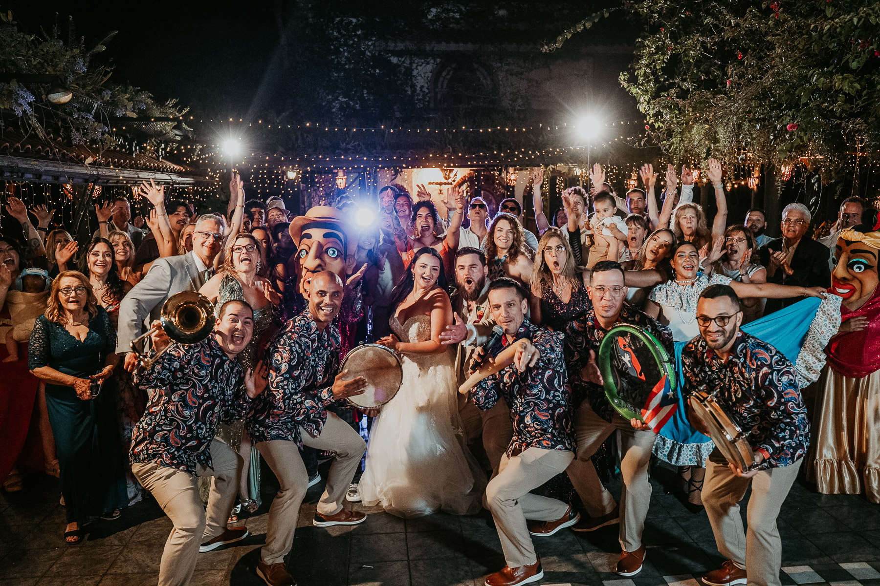 Candid fun picture of couple and wedding guests celebrating during reception beneath the lights at Hacienda Siesta Alegre