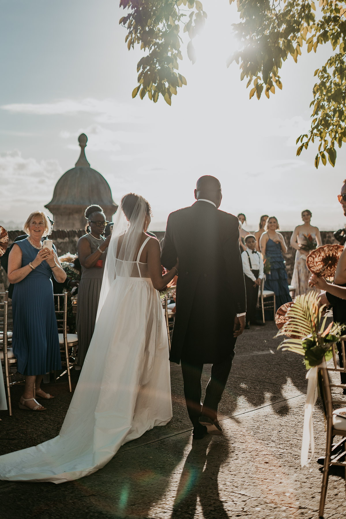 Bride walking down the aisle at La Rogativa accompanied by a parent.