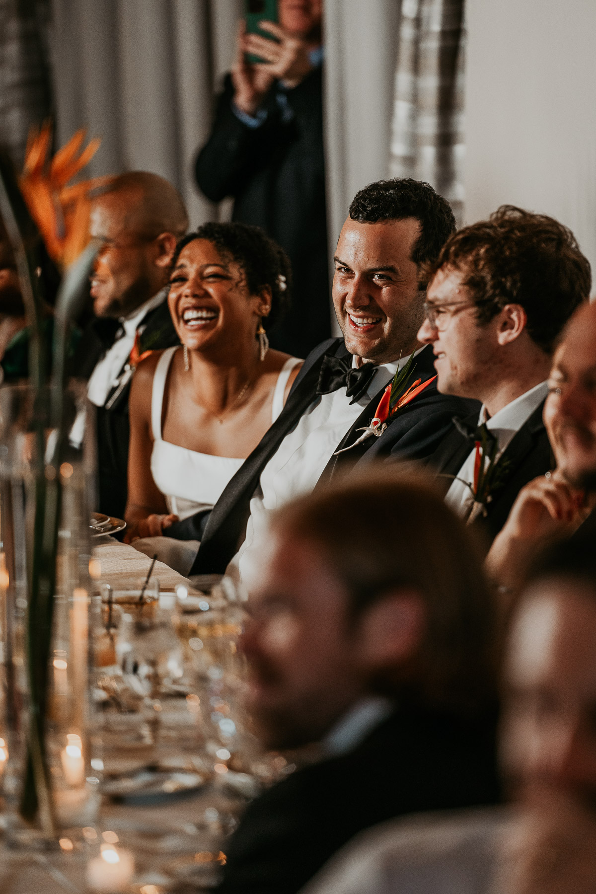 Bride and groom laughing together during a heartfelt toast.