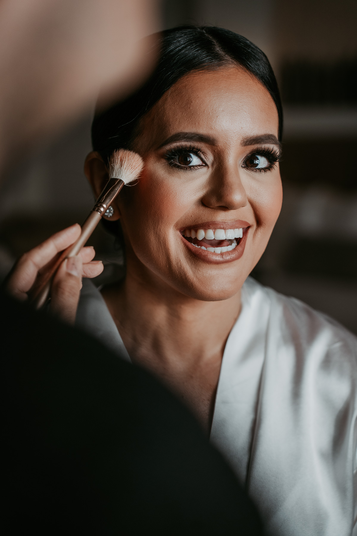 Candid photo of bride during hair and makeup.