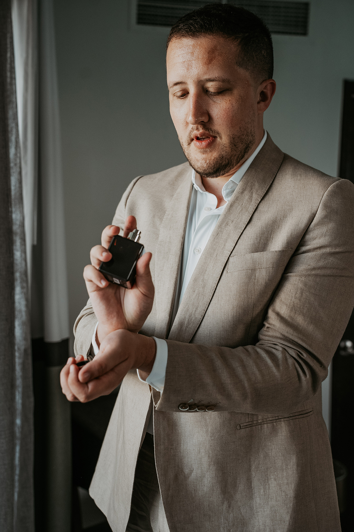 A bottle of perfume among the groom's wedding day details.