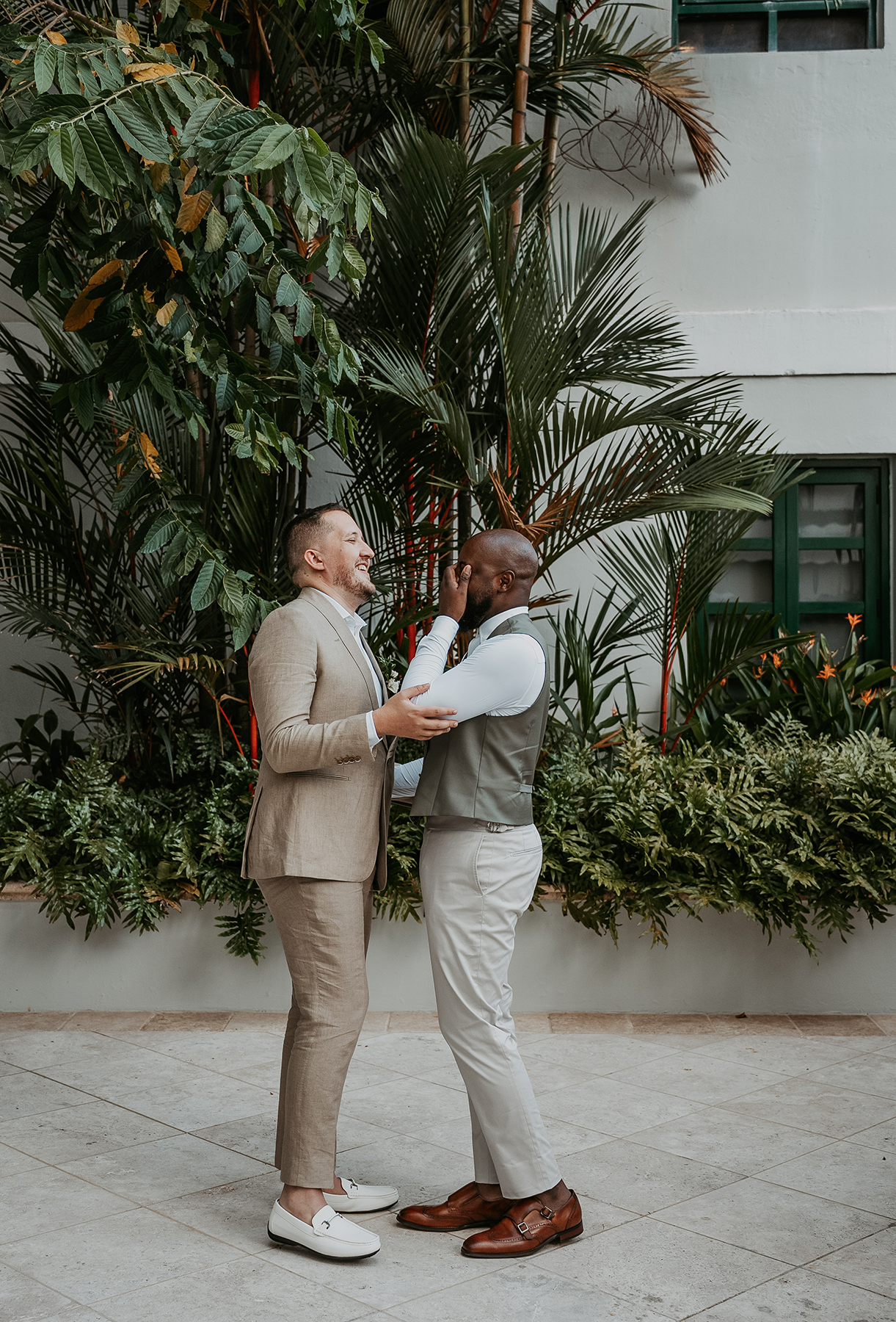 Two grooms hold each other close during a candid moment on their wedding day.