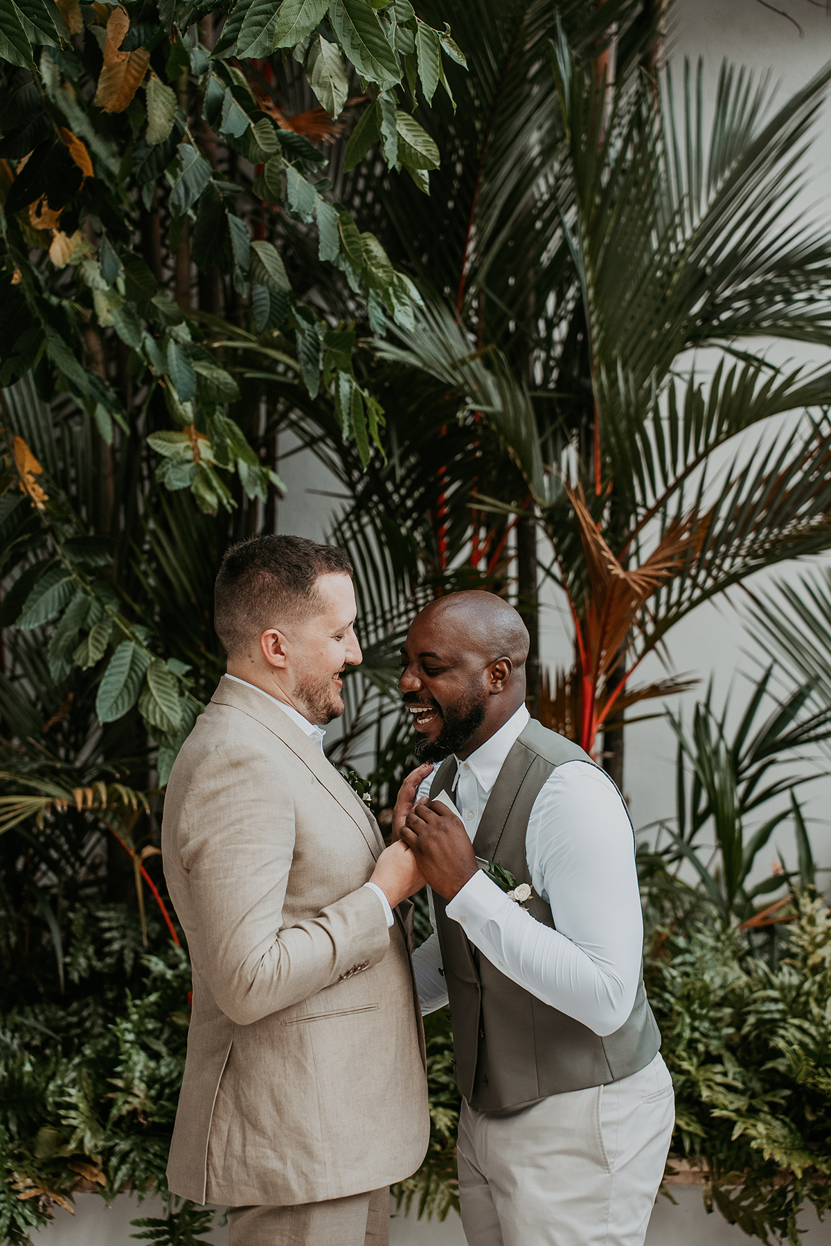 Two groom smile and embrace during their intimate first look.