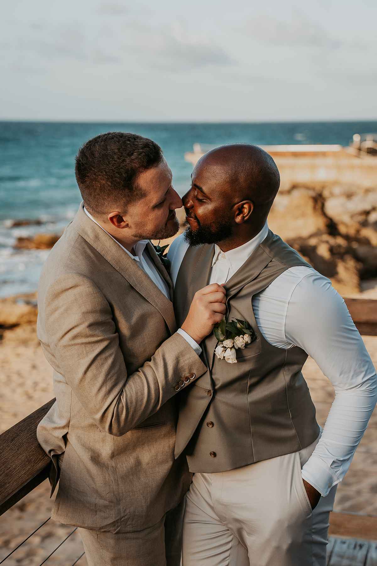 The newlyweds pose together outdoors at their oceanfront wedding venue.