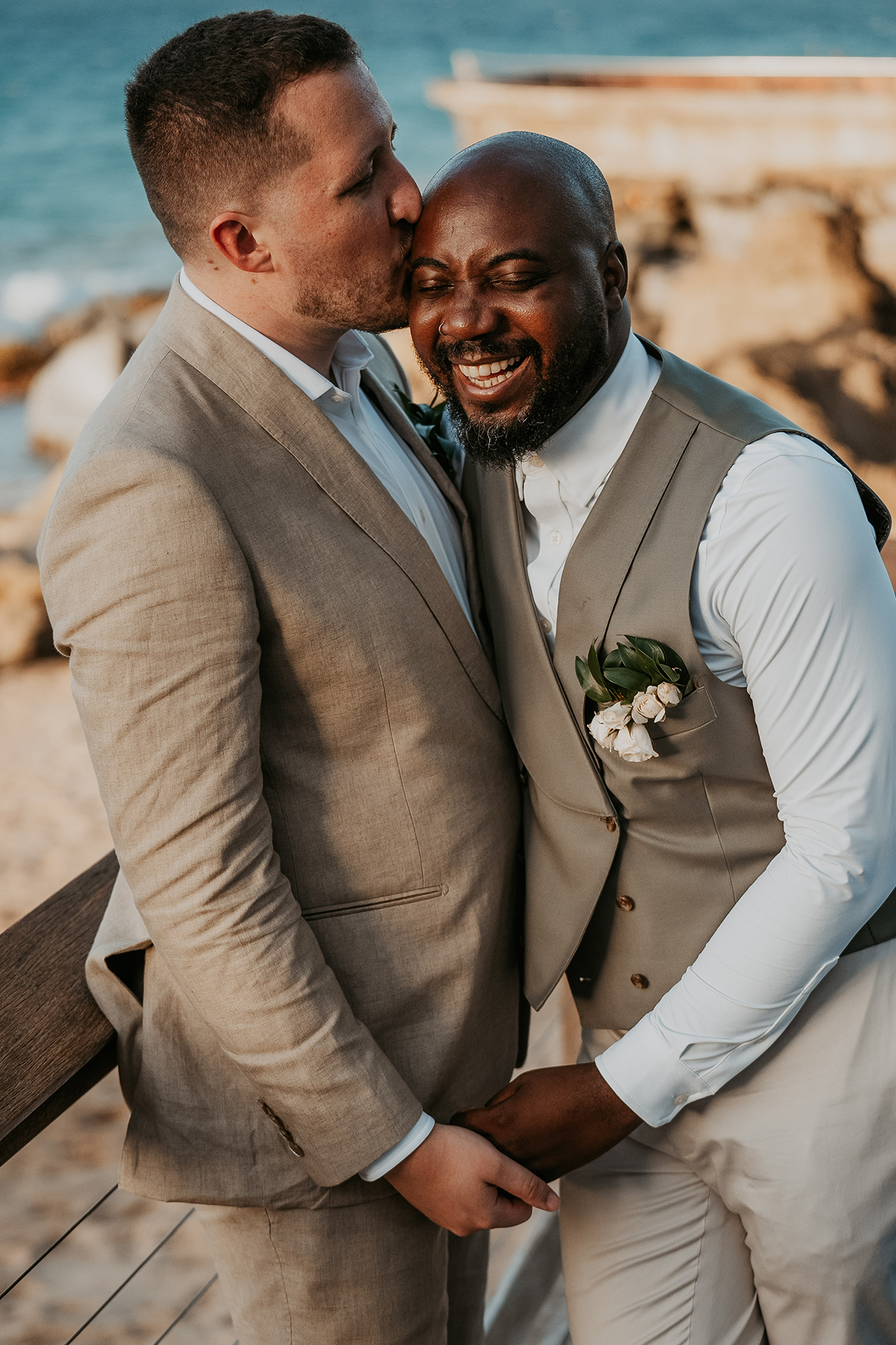 One groom kisses his husband's head during a tender wedding portrait.