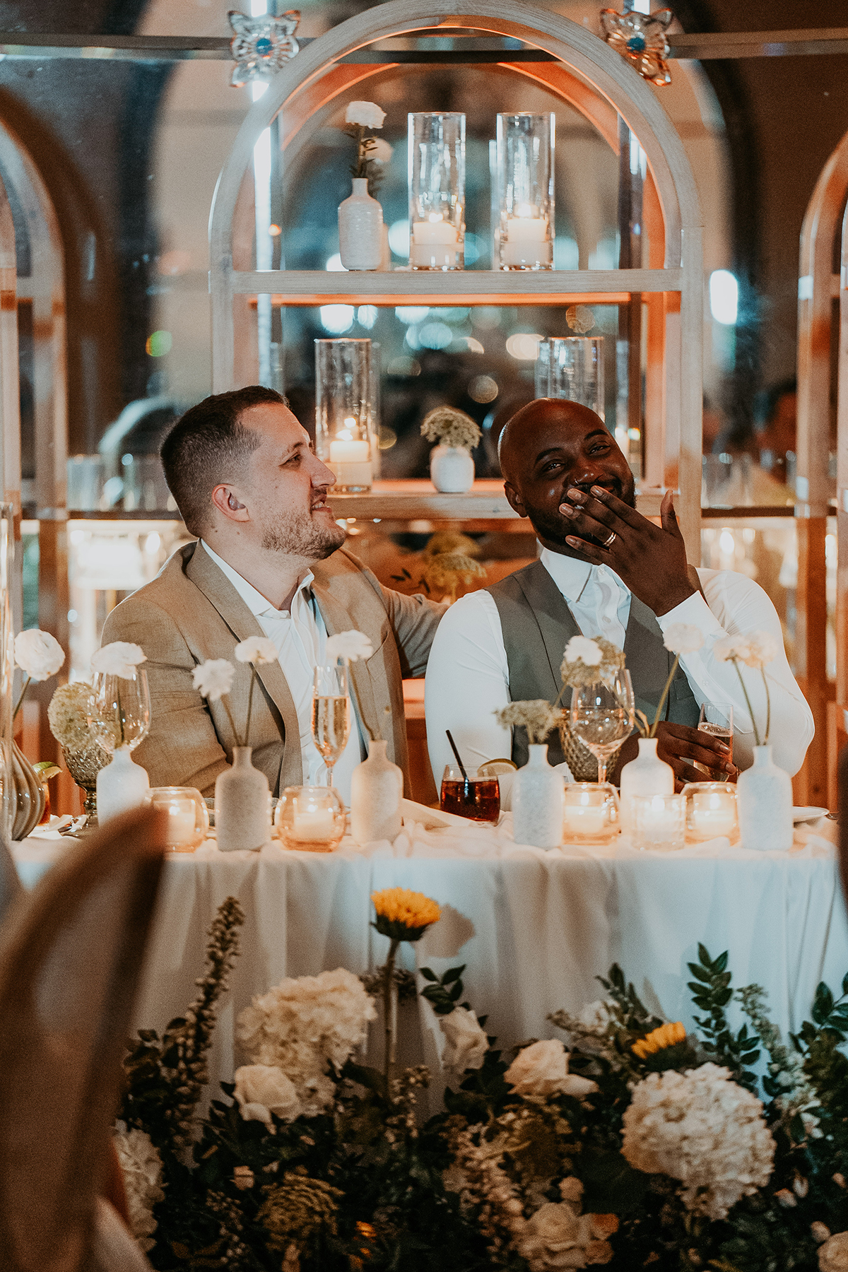 One groom raises a glass during a toast at their wedding reception.
