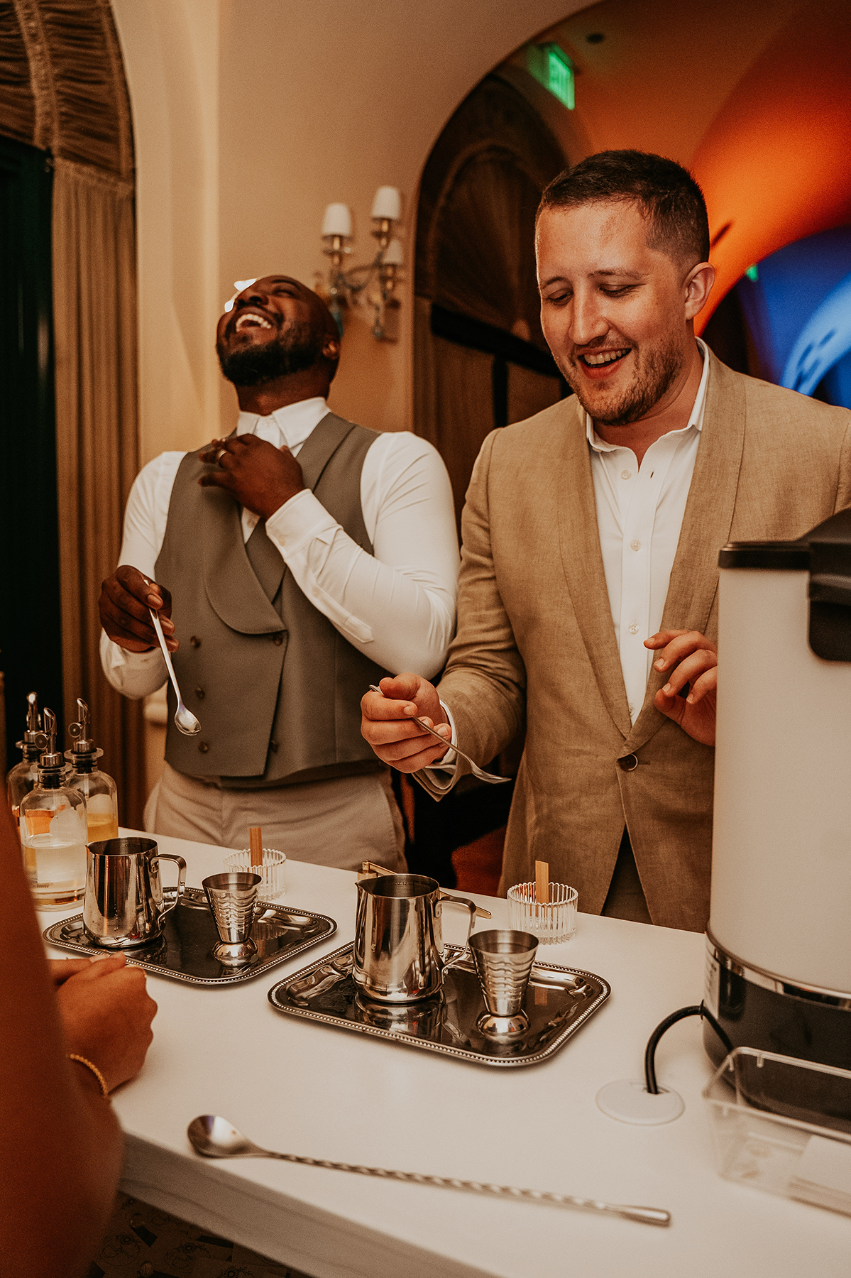 The grooms smile and interact with each other during their candle making station on their wedding celebration.
