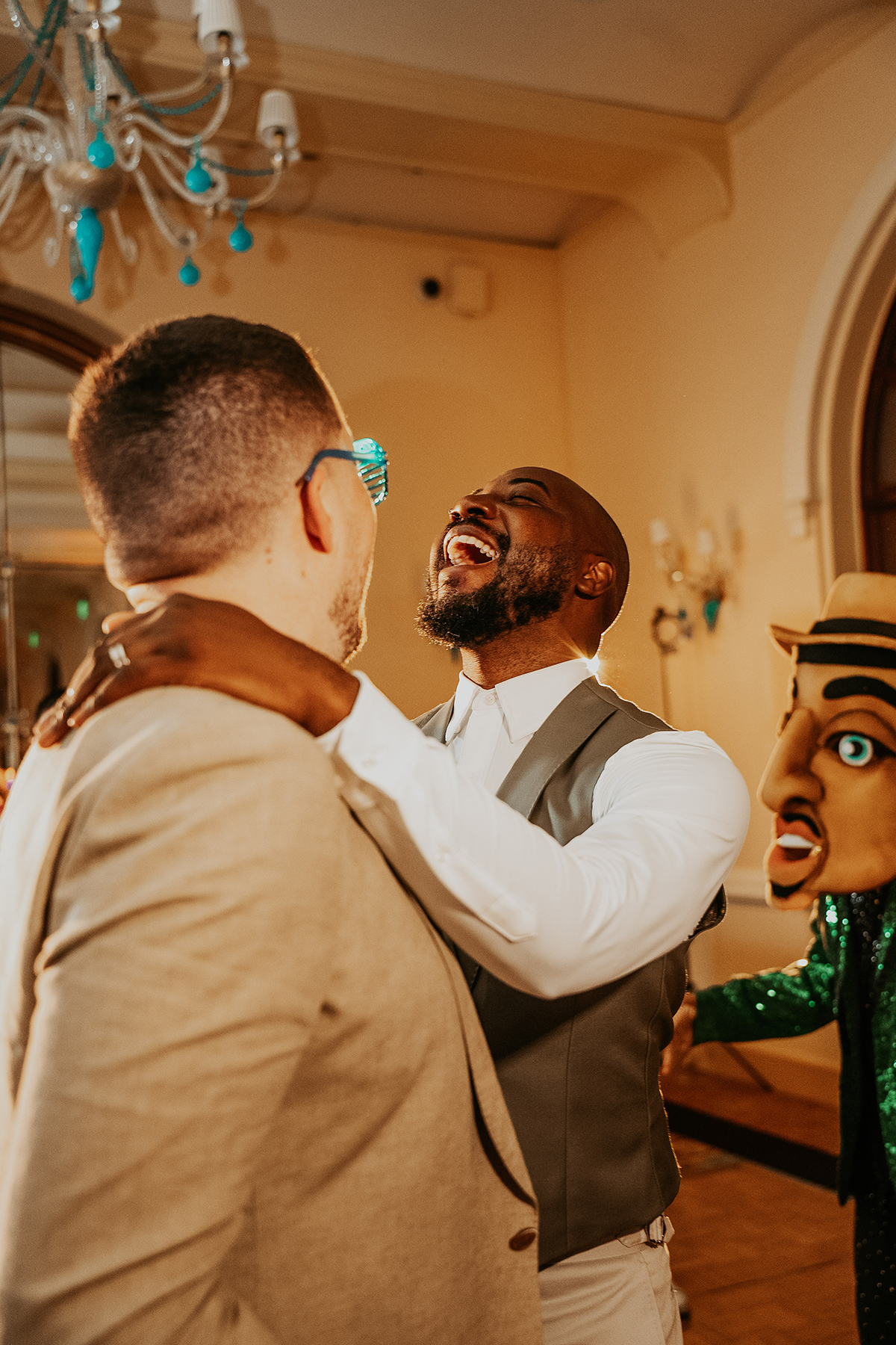 The grooms laugh together during dance in a candid moment on their wedding day.