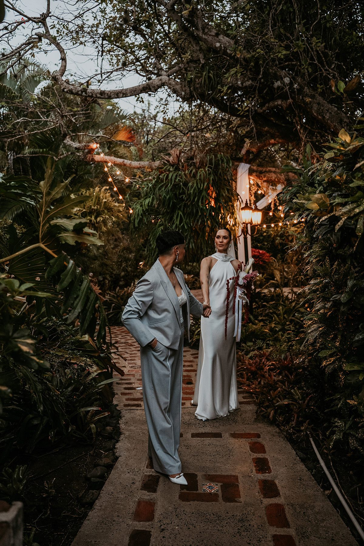 Two brides walking together through the gardens after their wedding