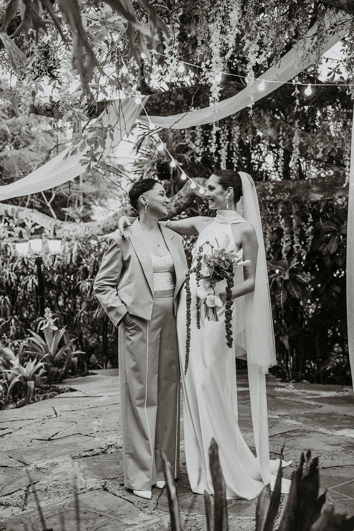 Black and white photo of newlywed couple posing together at Jardines del Castillo