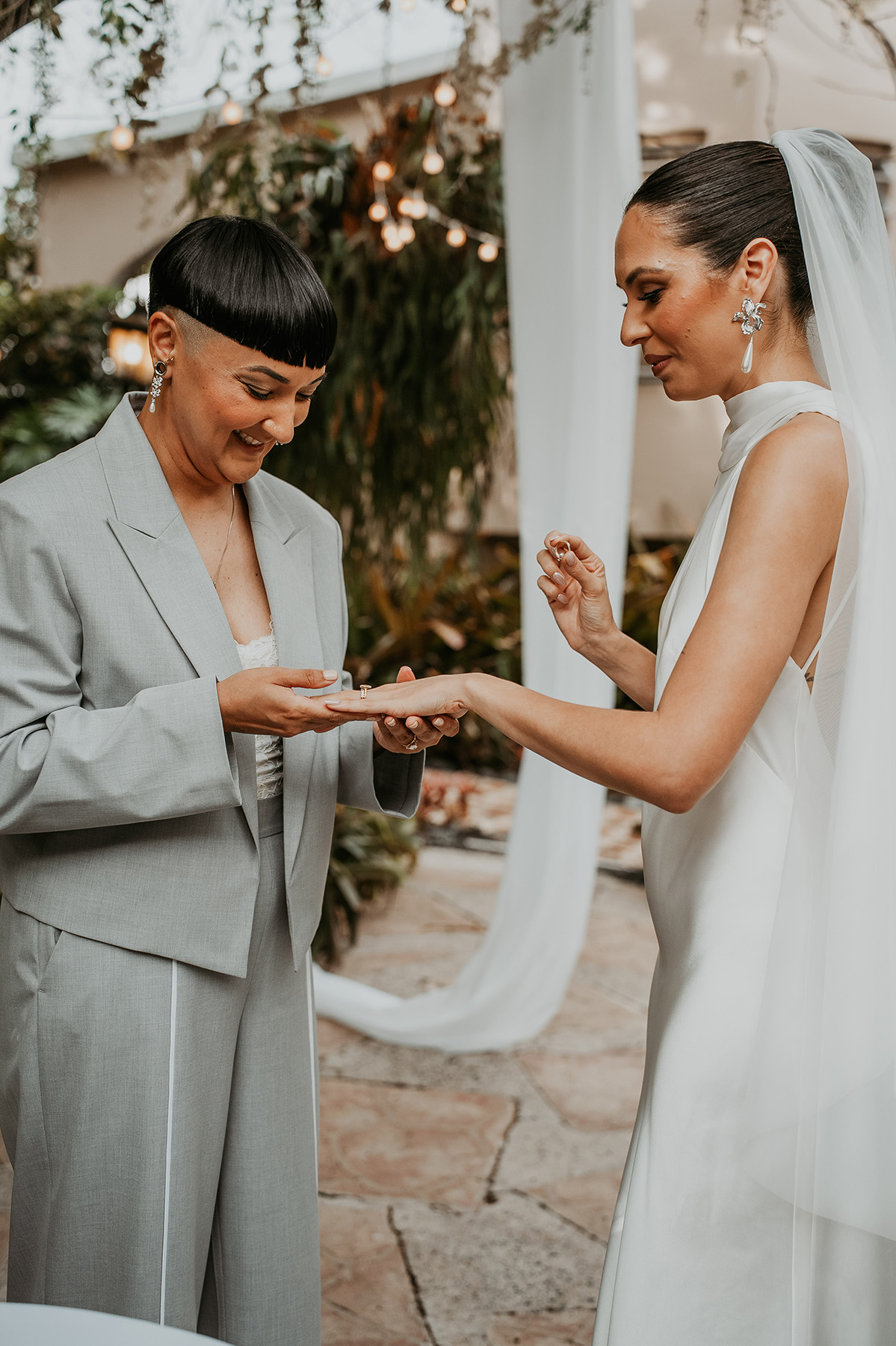 Two brides exchanging rings during their Jardines del Castillo wedding ceremony