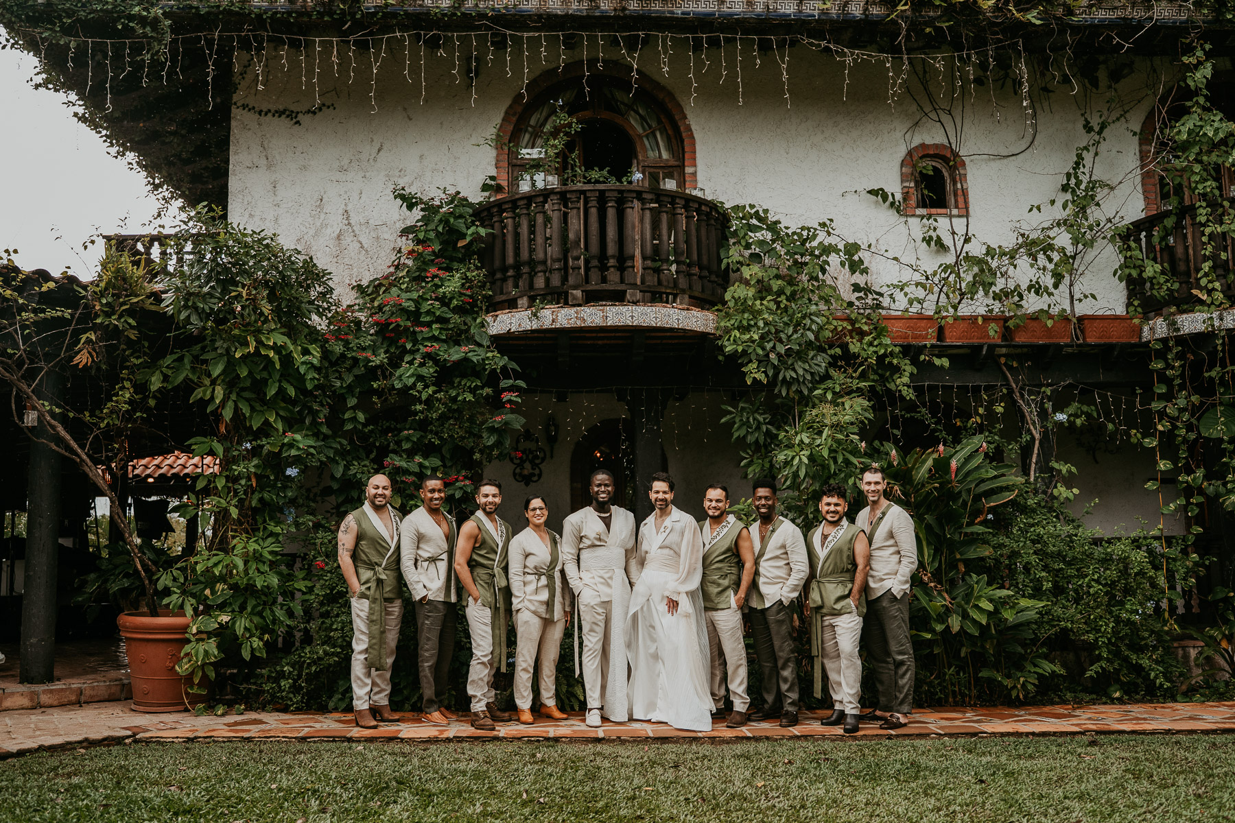 The couple posing joyfully with their wedding party, all dressed in coordinated outfits with the lush Hacienda Siesta Alegre. 