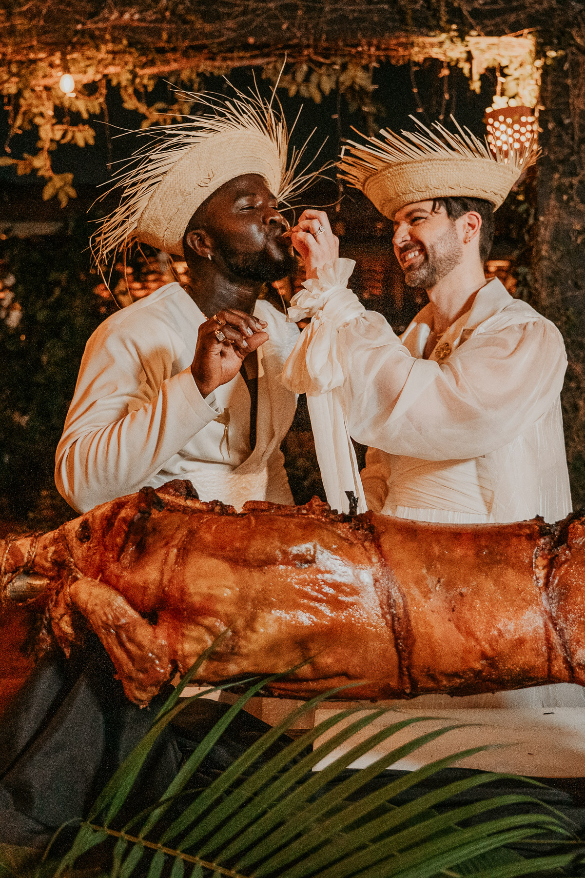 The couple cutting into a traditional Puerto Rican roasted pork, smiling as they share this festive culinary moment.