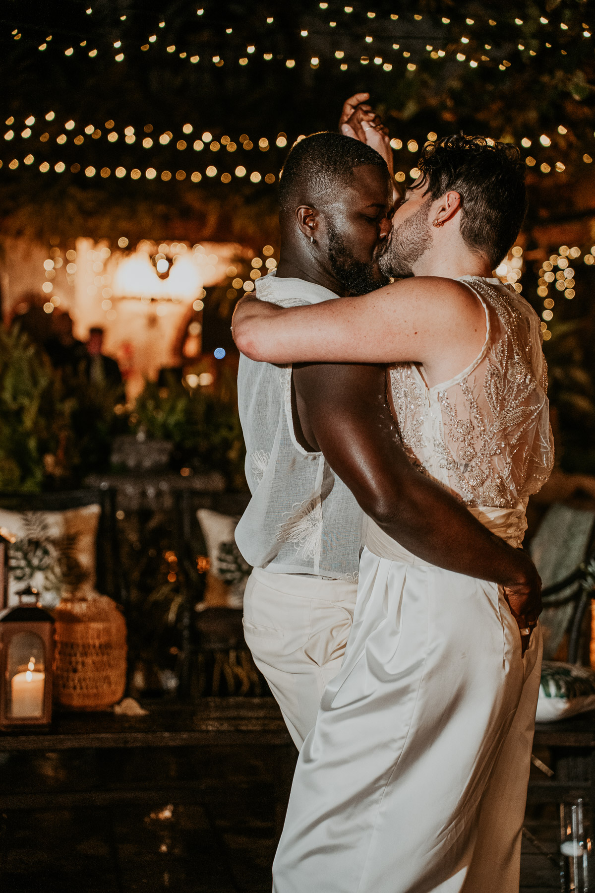 Partners embracing during their wedding reception, surrounded by friends and family.