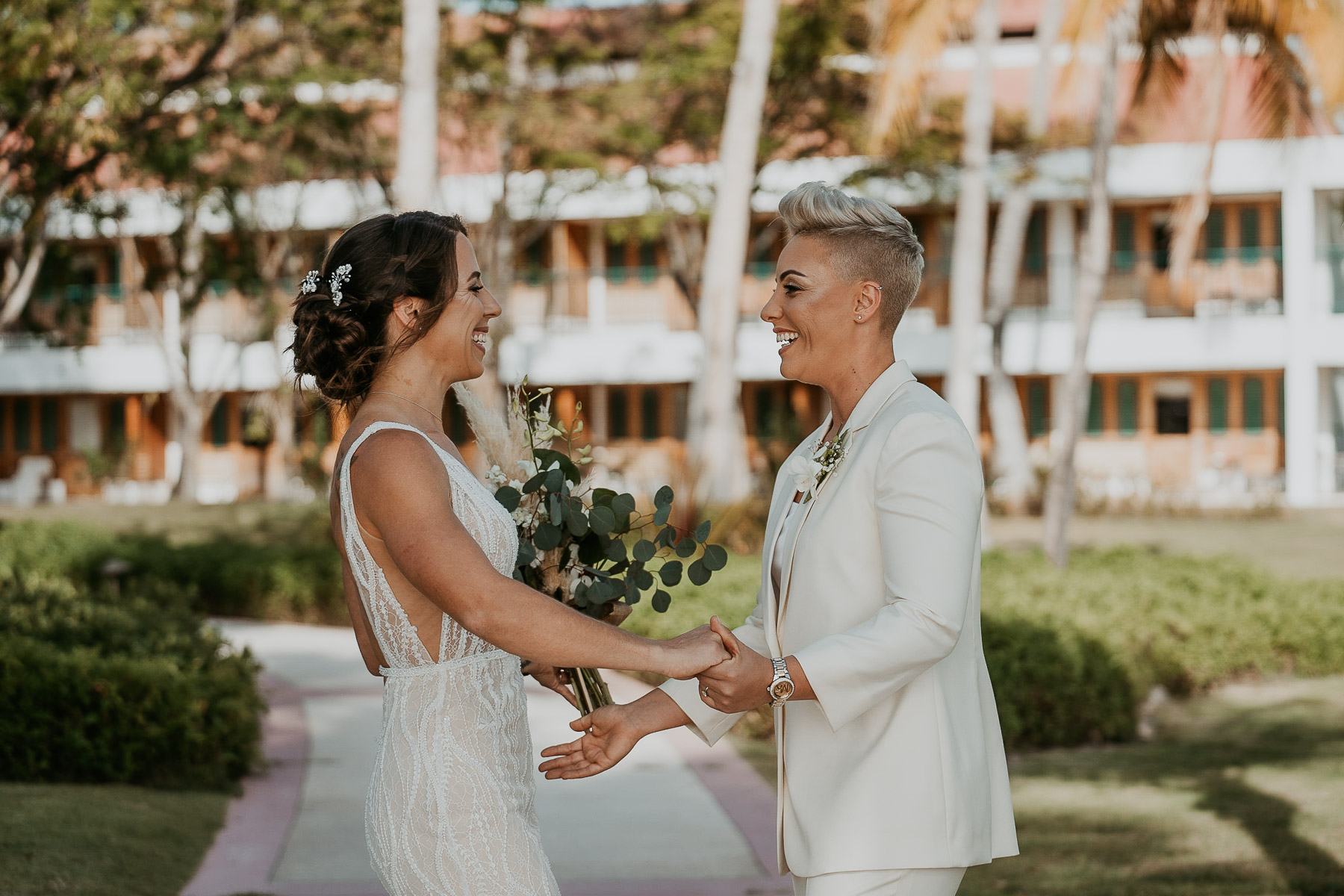 First look moment between two brides at Copamarina Beach Resort garden.