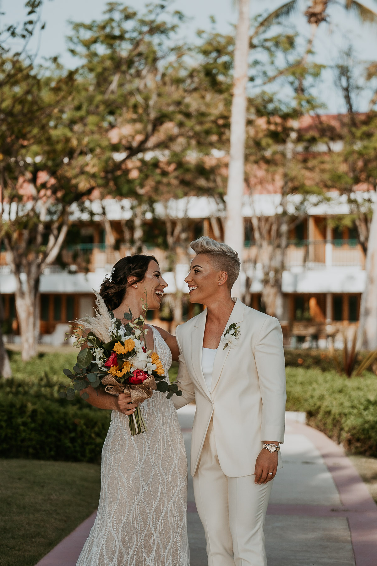 First look moment between two brides at Copamarina Beach Resort garden.