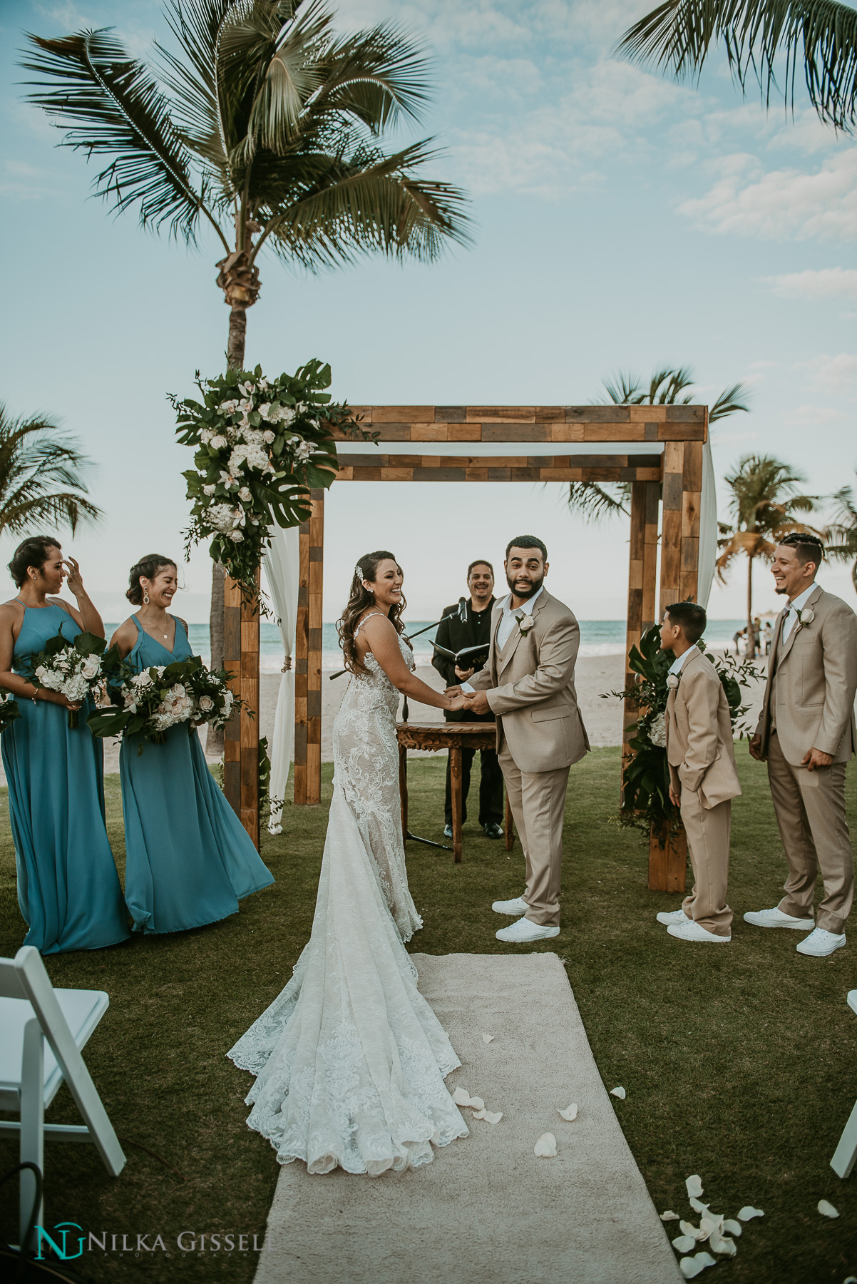 A couple on the beach with a wedding photographer capturing their ceremony