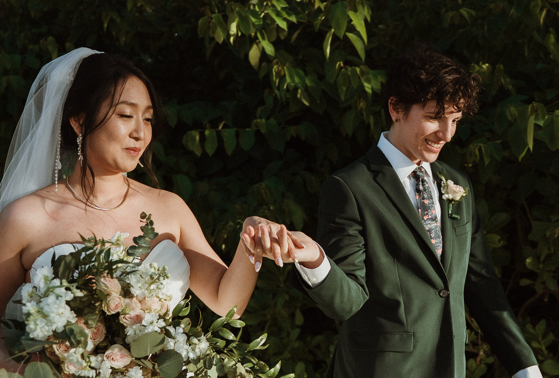 The joyful lesbian couple walking down the aisle hand-in-hand as newlyweds.