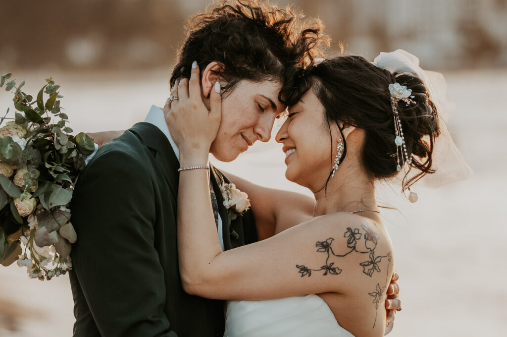 Candid photo of lesbian couple embracing each other on the coastline.
