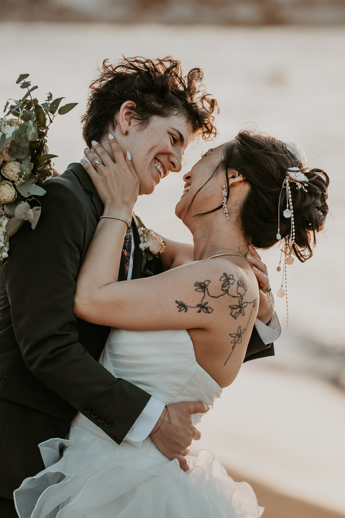 The newlyweds sharing a romantic embrace on the sand at an open beach wedding venue.