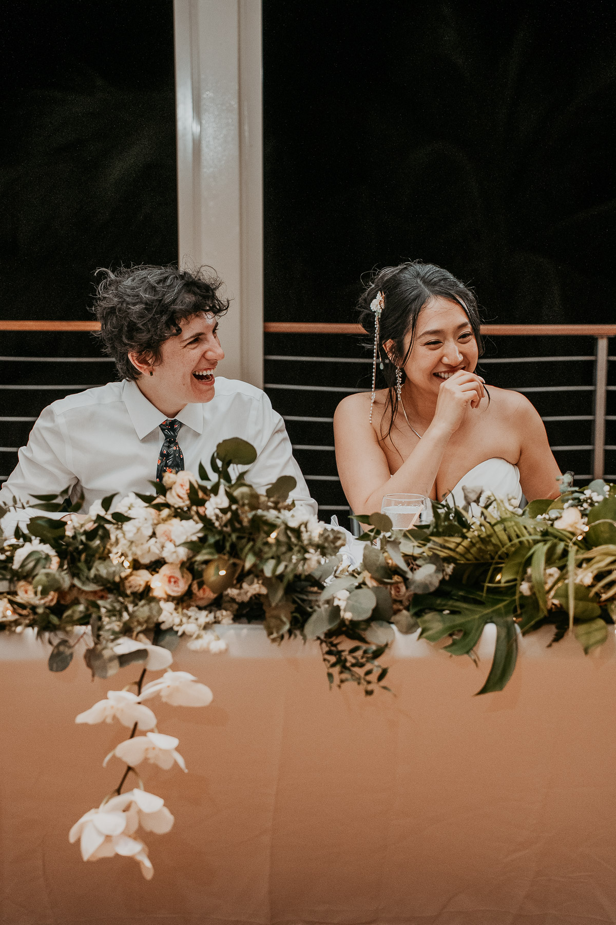 The newlyweds sitting at their sweetheart table smiling during their reception.