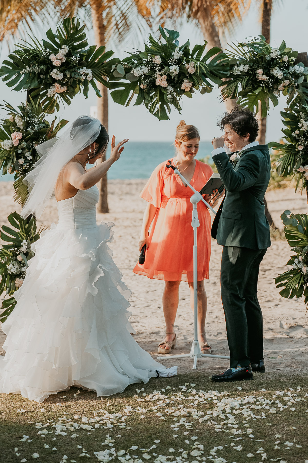 The lesbian couple breaking the glass under the chuppah at their multicultural wedding.